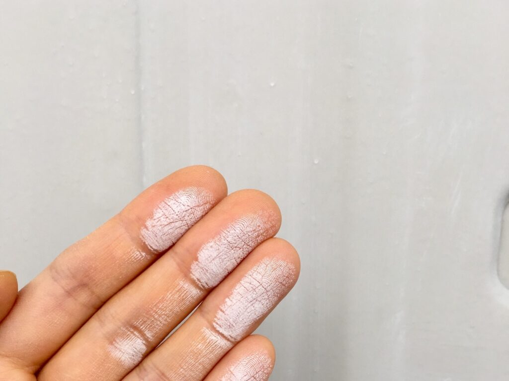 チョーキング現象で外壁を触って手に塗料の粉がついている写真