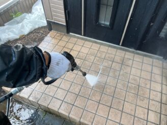 玄関前のタイルの高圧洗浄をしている様子の写真
